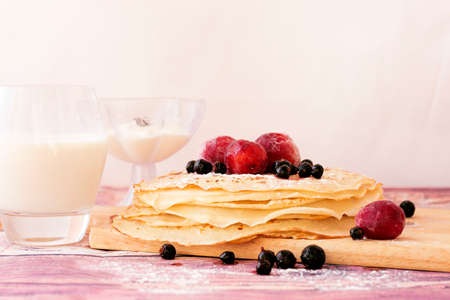 Stack of kefir (buttermilk) pancakes with black currant, plum, milk and sourcream. Traditional food for Russian pancake week.の写真素材
