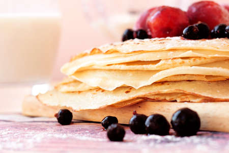 Buttermilk pancakes with black currant and plum on wooden plate closeup.の写真素材