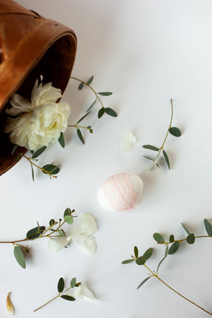 Minimalistic Rustic Composition with egg decorated a ribbon lace, green twigs of eucalyptus,...