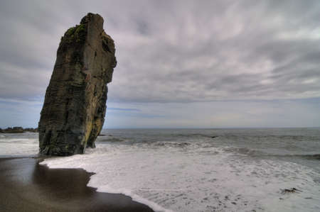 Lonely beach with a big inclined rockの写真素材