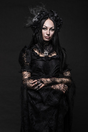 Portrait of beautiful Gothic woman in dark dress in studioの写真素材