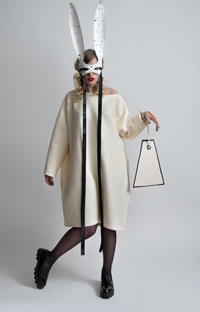 Beautiful tender woman in fashion clothing with rabbit ears on grey backgroundの写真素材