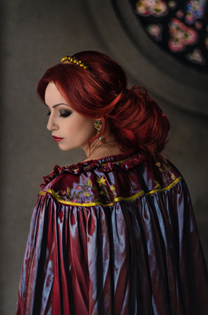 Woman with red hair wearing elegant royal garb and golden crownの写真素材