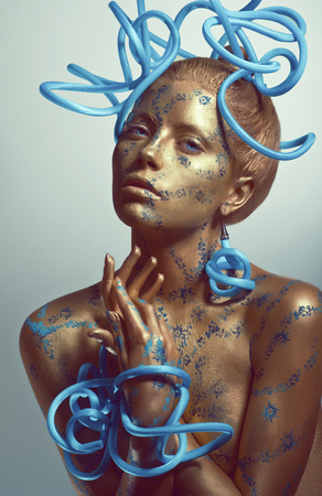 Woman with golden body-art and blue tubesの写真素材