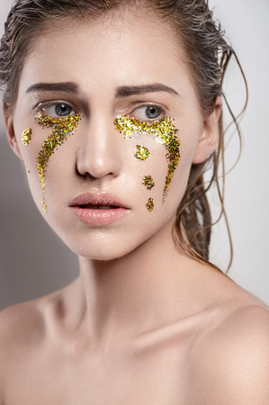 Girl with golden tear drops on faceの写真素材
