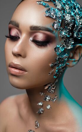 Closeup portrait of girl with silver foil pieces body artの写真素材