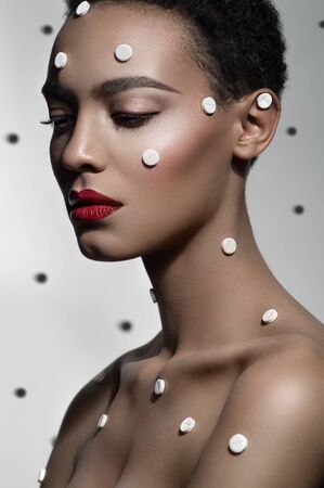 Girl with dots on face on dotted white backgroundの写真素材