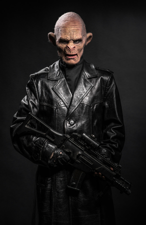 Angry baboonish man in black clothes on dark backgroundの写真素材