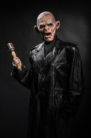 Angry baboonish man in black clothes on dark backgroundの写真素材