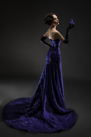 Young beautiful brunette woman posing with perfume bottleの写真素材