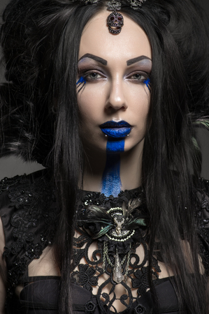 Young woman in black fantasy costume with feathers on dark backgroundの写真素材