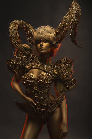 Beautiful devil women with golden ornamental horns on dark backgroundの写真素材