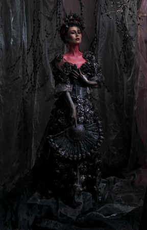 Dark queen in black fantasy costume on dark gothic backgroundの写真素材