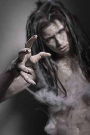 Dirty zombie woman with clay make up on dark backgroundの写真素材