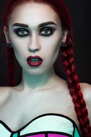 Fashion studio portrait of beautiful redhead woman with dark makeup, wearing bright swimweaの写真素材