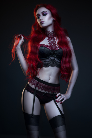 Beautiful gothic woman in lingerie posing at camera on black backgroundの写真素材