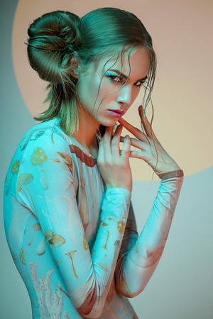 Portrait of blonde woman in blue bodysuit with mushrooms posing at cameraの写真素材