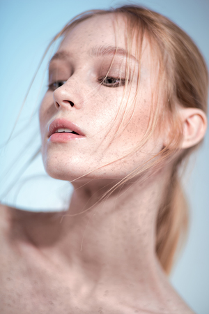 Portrait of beautiful blonde woman with nude makeup against blue backgroundの写真素材