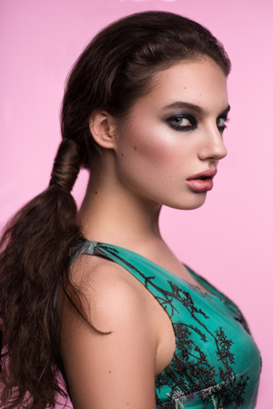 Woman in green dress with black branches looking at camera against pink backgroundの写真素材