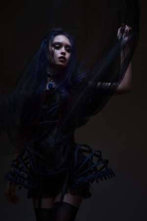 Woman with red hair and black veil posing on dark backgroundの写真素材