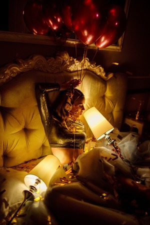 Woman laying on sofa with lamps and air balloons after partyの写真素材