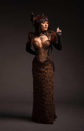 Full length view of brunette woman in gothic steampunk gown posing at cameraの写真素材