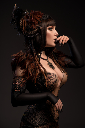 Side view of brunette woman in gothic steampunk gown posing at cameraの写真素材