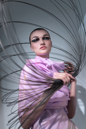 Portrait of woman in pink dress posing at camera with thin circlesの写真素材