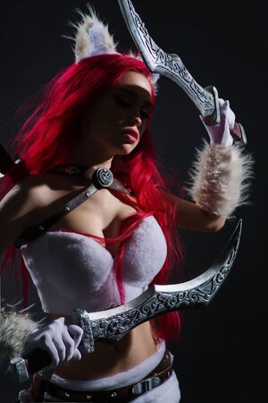 Sexy redhead woman in cosplay costume of warrior cat with swords posing on dark backgroundの写真素材