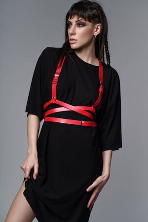 Studio portrait of woman in fashion clothes and red harnessの写真素材
