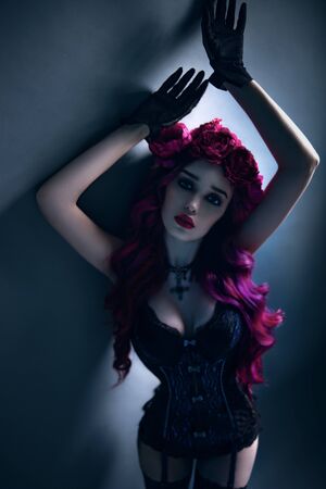 Attractive woman with bright pink hair and flower wreath made of peonies in lingerie on grey backgroundの写真素材
