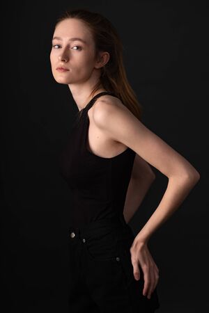 Beautiful brunette model in black clothes posing on dark studio backgroundの写真素材