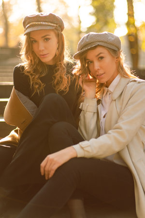Young sisters sitting on stairs in fashion clothes. Fall pictureの写真素材