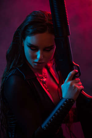 Longhair vampire in black long corset dress in smoke holding a gunの写真素材