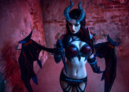 Girl devil in gothic costume and wings posing next to the brick wallの写真素材