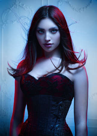 Woman in elegant dress and long hair posing in studioの写真素材