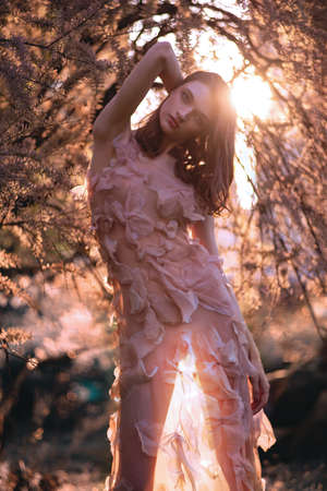 Beautiful young model posing in spring park in pink dressの写真素材