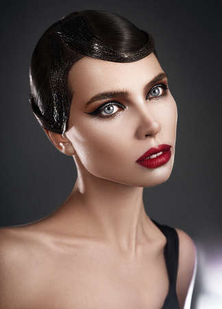 Attractive brunette with retro hair style and beautiful makeup with red lips. Close up portraitの写真素材