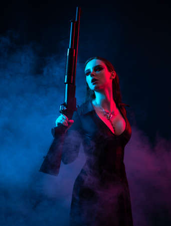 Longhair vampire in black long corset dress in smoke holding a gunの写真素材