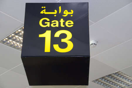 Ceiling sign of gate 13 (thirteen) in Arabic and English in an Arab airport lounge, spelling bad luck, a mishap or misfortune on the flight (Doha, Qatar, code DOH).の写真素材