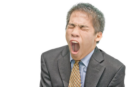 Portrait of intensely yawning tired and overworked young Asian businessman or salesman in formal attire, frowning with wide open mouth and eyes closed. Isolated over white with copyspace.の写真素材