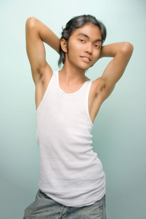 East Asian teenager boy in sleeveless shirt and jeans striking a cheering and smiling glamor pose...