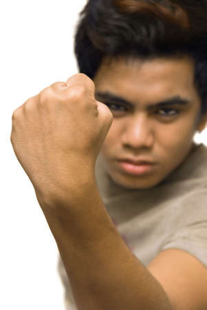 Masculine clenched closed fist close-up in an aggressive macho gesture, in focus with a blurred determined face in the background. Isolated over white.の写真素材
