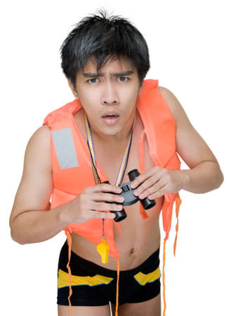 Worried and watchful Asian young lifeguard bending over and attentively holding binoculars spotting a dangerous situation, in red life or swimming jacket. Isolated over white.の写真素材
