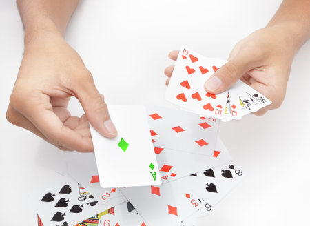 Hands holding and showing playing cards on white table background, playing the green ace card....