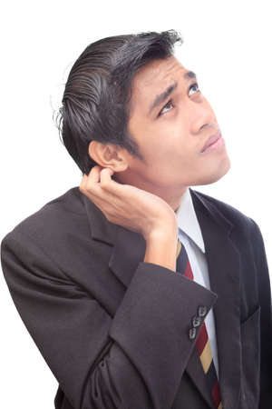 Insecure junior Asian businessman standing in doubt portrait, scratching his ear in conflict. Isolated over white.の写真素材