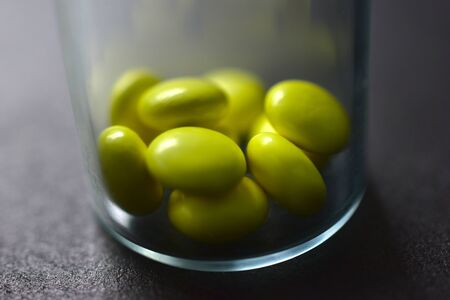 Tablets in a glass bottle on a black backgroundの写真素材