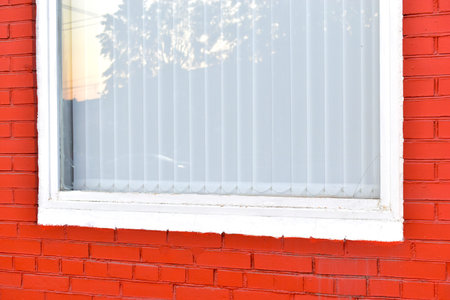 A house with a red painted brick wall and white Windows