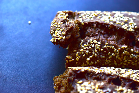 A loaf of black bread with sesame seeds on a black background