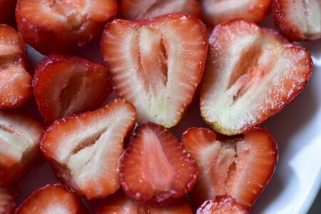 Large delicious Victoria berries and sliced Victoria berries on a white plateの写真素材